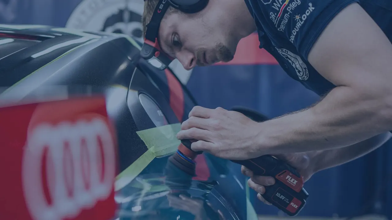 Aufbereiter poliert mit einer kleinen Poliermaschine die abgeklebte Kante an einem Audi
