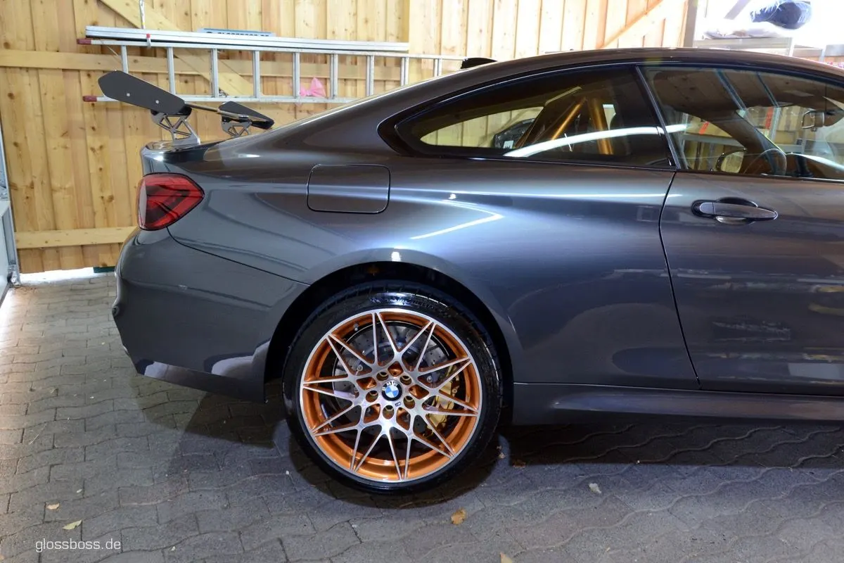 Grey sports coupe with orange wheels parked on paving stones after a detail