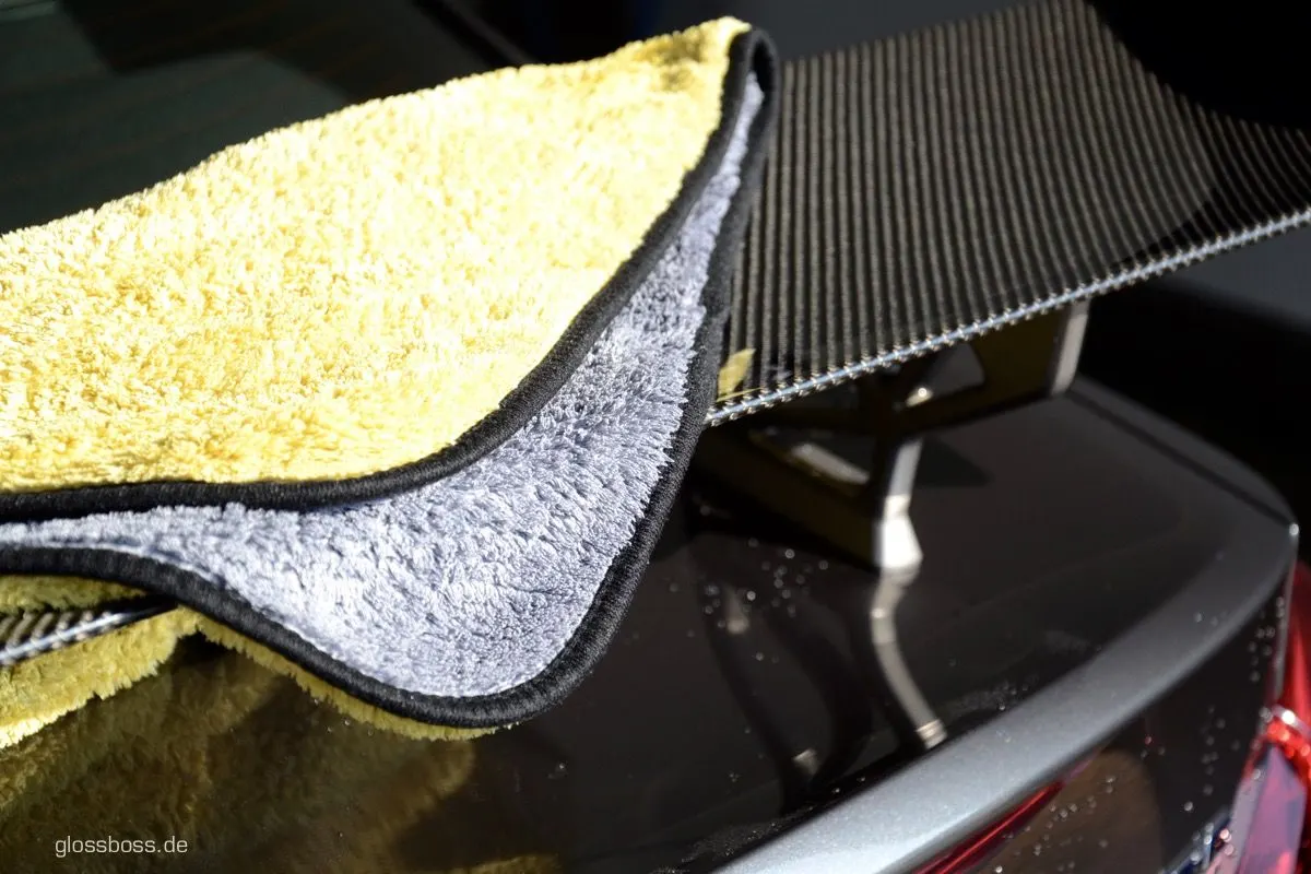 Yellow microfiber towel folded over the edge of a freshly washed dark car