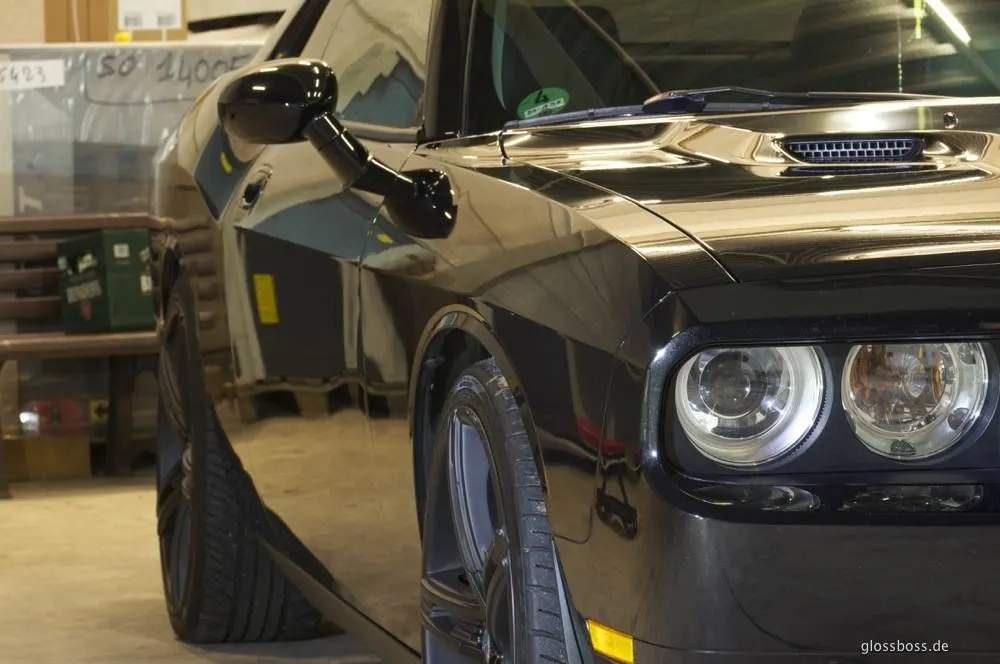 Black muscle car in a garage, paint reflecting like a mirror after polishing