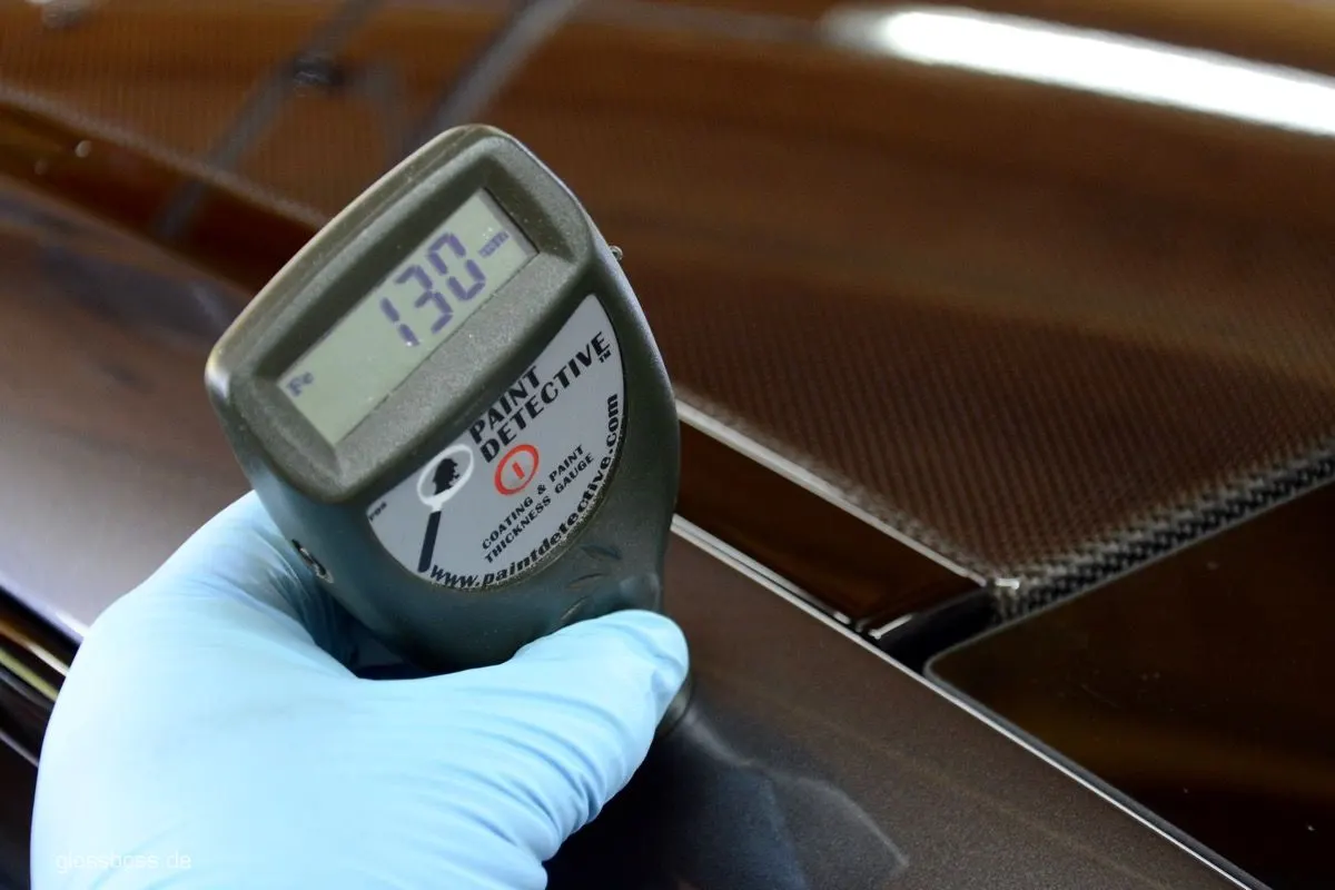 Paint thickness gauge held against a car panel before polishing