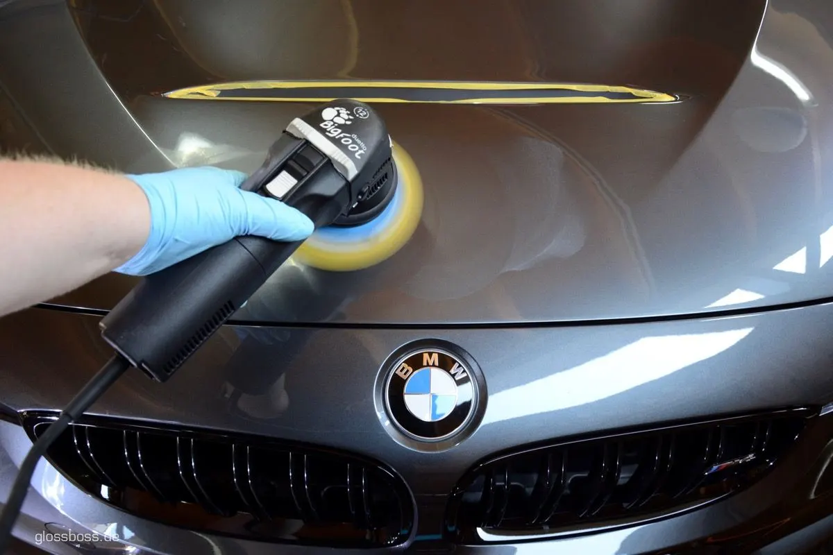 Detailer machine polishing the hood of a grey coupe with a dual-action polisher